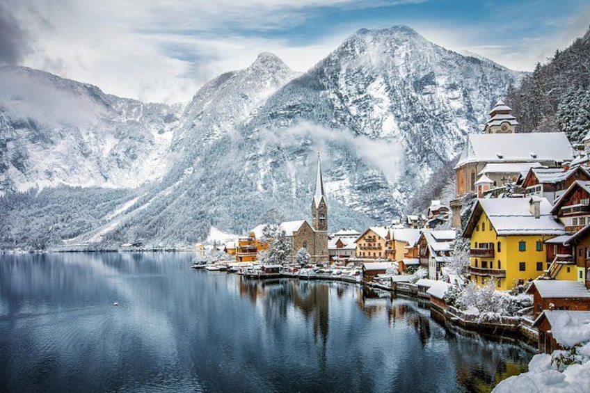 A snow-covered village by a lake with mountains in the background. 2