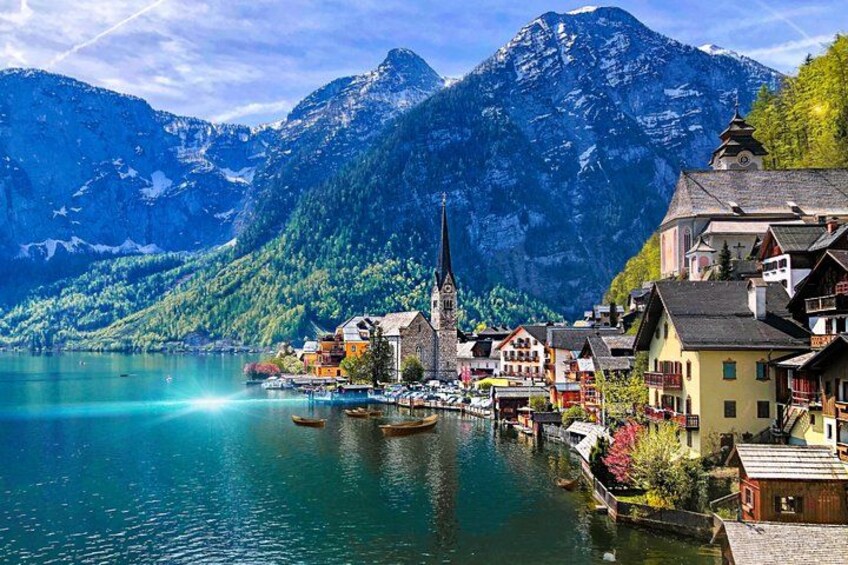A lakeside town with colorful buildings, a church, and mountains in the background. 1