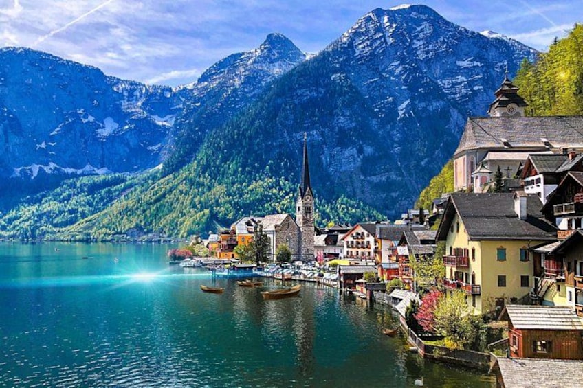 A lakeside town with colorful buildings, a church, and mountains in the background. 1