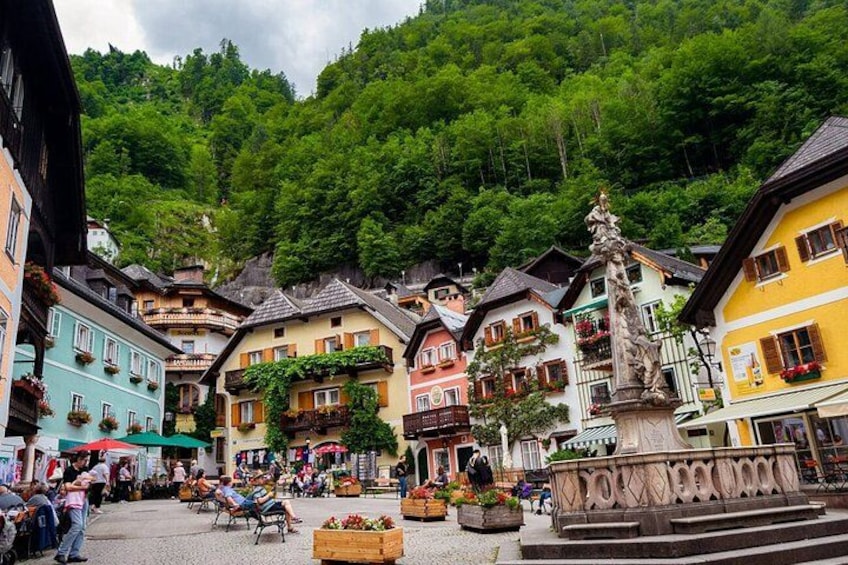 A European village square with colorful buildings, a fountain, and a hill in the background. 3
