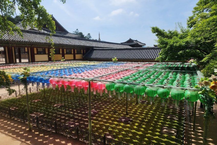 A traditional building with a tiled roof, surrounded by a garden with rows of colorful lanterns. 4