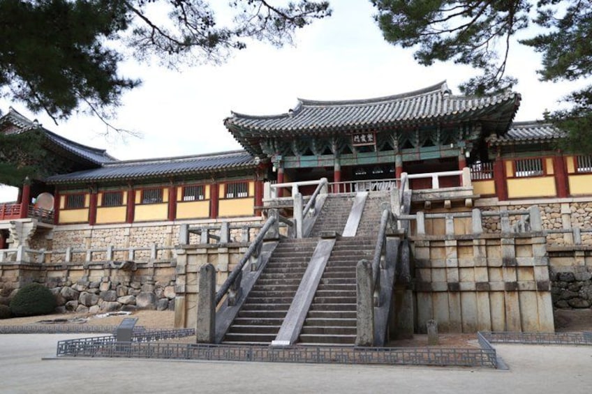 A traditional Korean building with a stone staircase leading to a tiled roof. 3