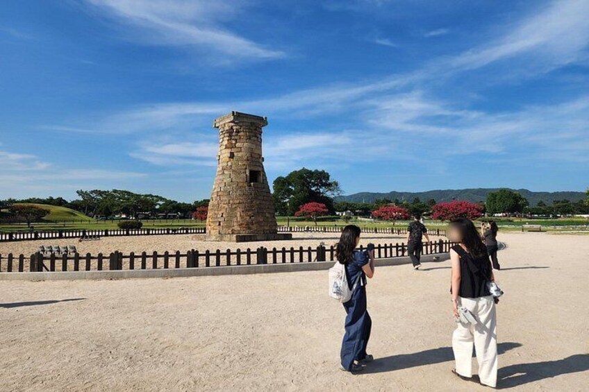 Una torre de piedra, un área cercada y gente caminando. 2