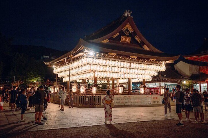 A traditional Japanese building with a tiled roof and illuminated lanterns. 2