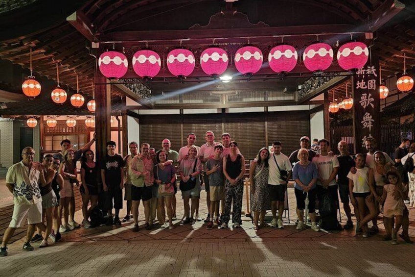 A group of people standing under a traditional structure with red lanterns. 3