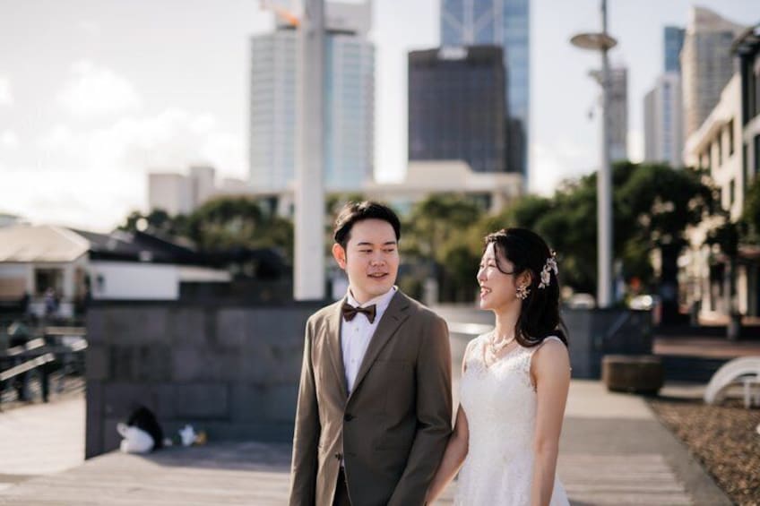 A couple in wedding attire on a city street with modern buildings in the background. 3