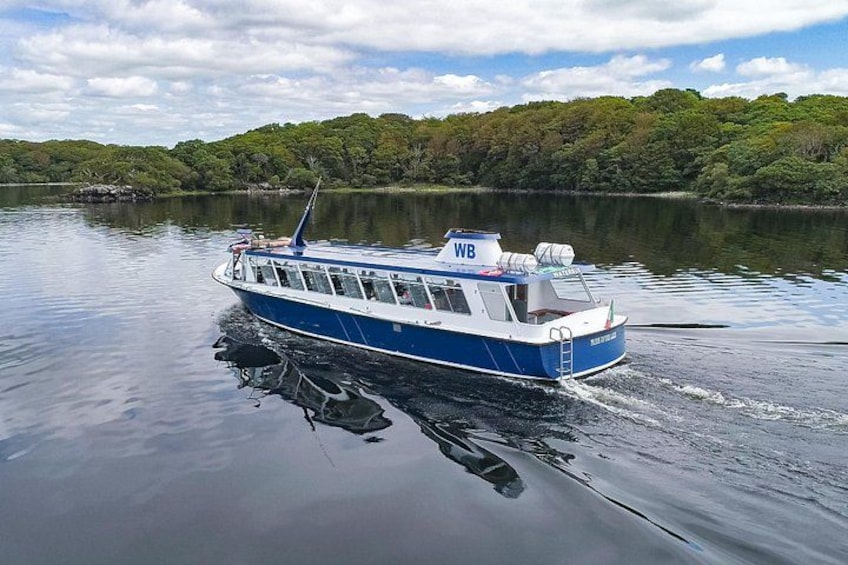 Ein blau-weißes Boot mit der Kennung WB, das sich auf ruhigem Wasser bewegt, mit einer bewaldeten Uferlinie im Hintergrund. 2