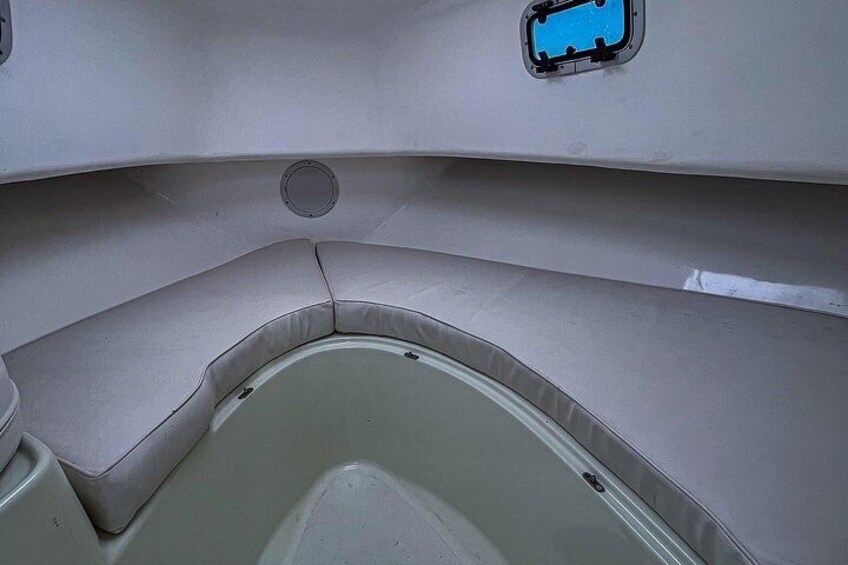 Interior de un barco con una zona de asientos acolchada y una ventana pequeña. 3