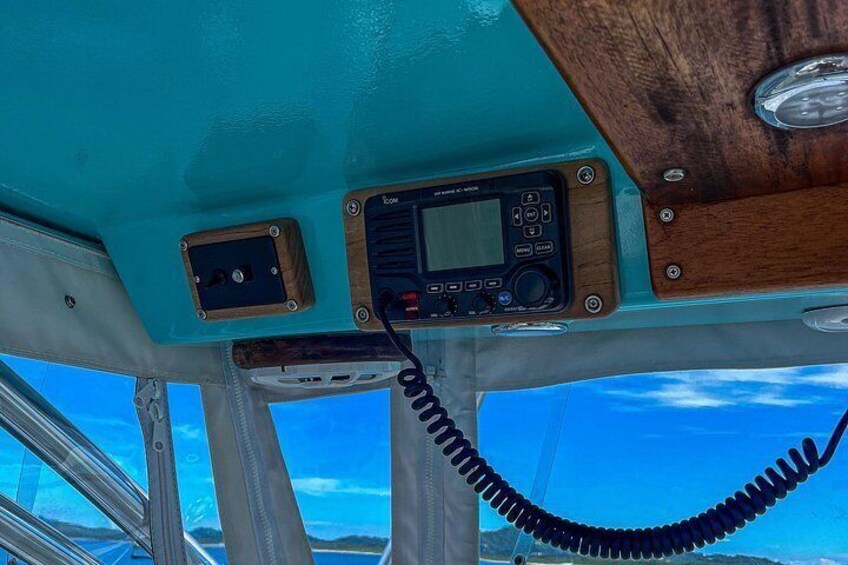 Interior de un barco con una radio, una antena enrollada y un panel de madera. 4