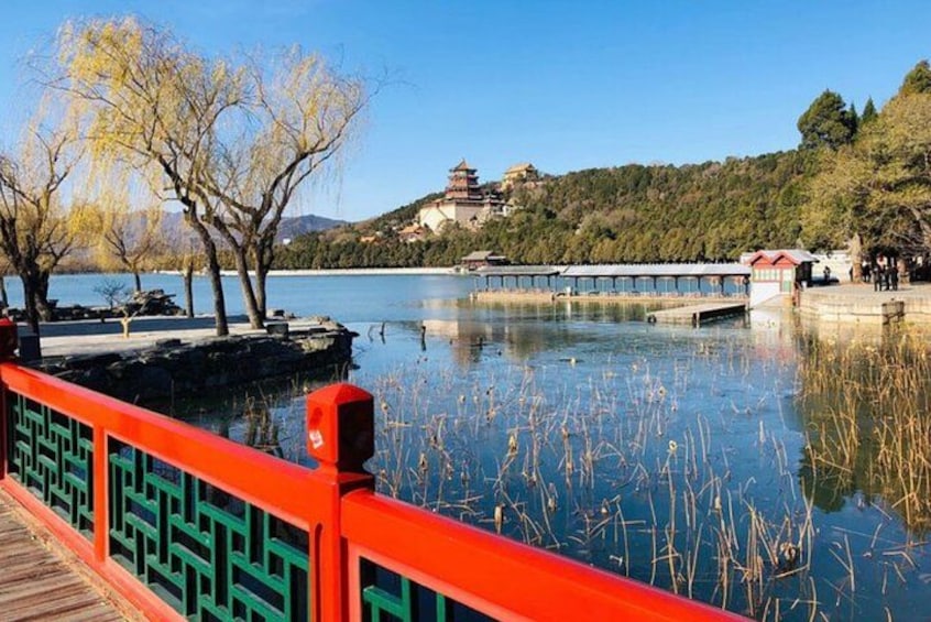 A serene lake with a red bridge, trees, and a distant pagoda. 2