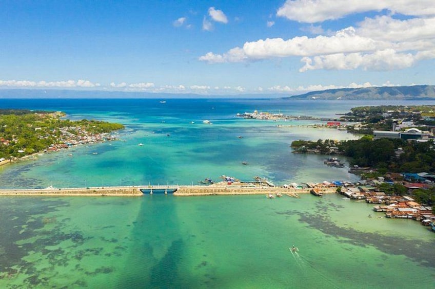 A coastal town with a bridge, clear turquoise waters, and a distant mountain range. 4