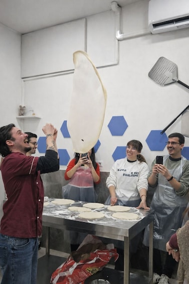 A group of people in a kitchen, one person holding a large white object above their head. 1