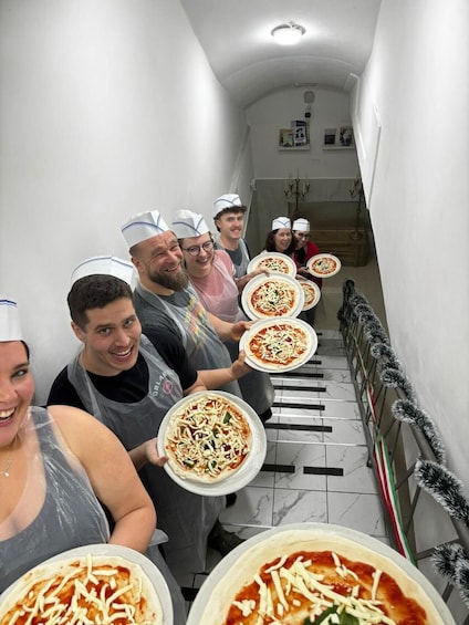 A group of people in a corridor holding pizzas. 3