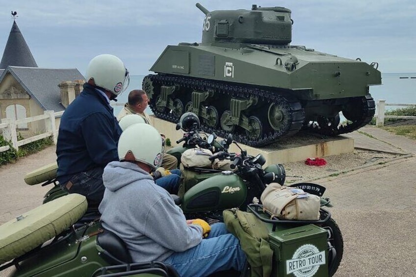 Un tanque militar exhibido con gente sentada en motocicletas al frente. 4