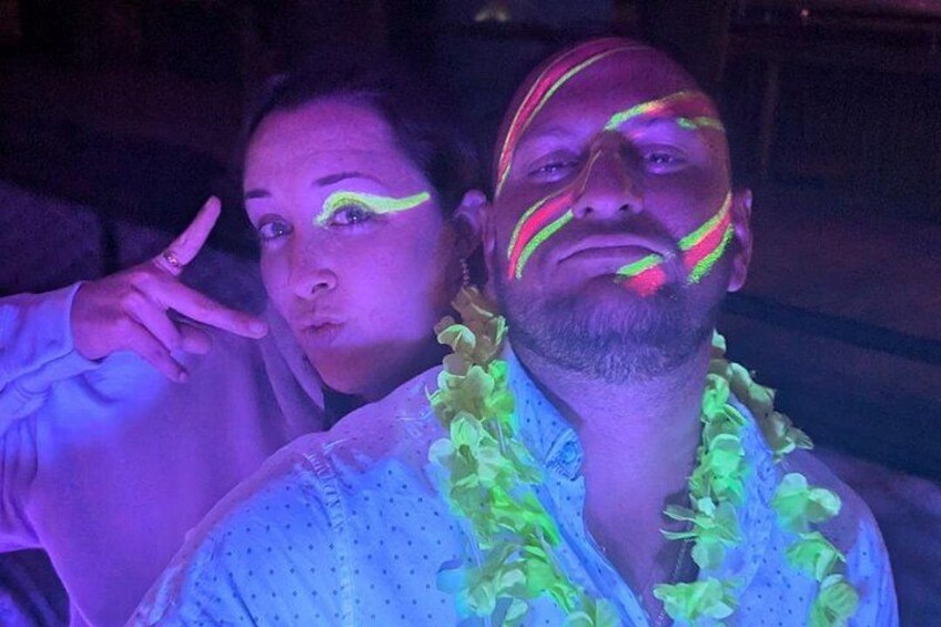 En person med neonlys maling i ansigtet og en lei om halsen. 3