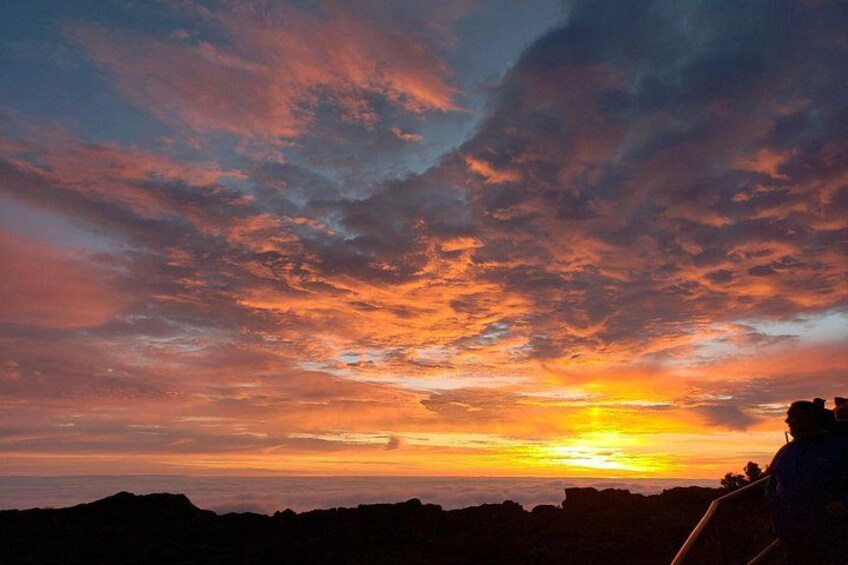 Un coucher de soleil avec la silhouette d’une personne et une chaîne de montagnes. 2