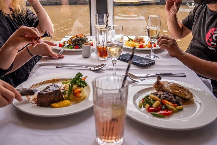 A dining table with plates of food, glasses of beverages, and cutlery. 1