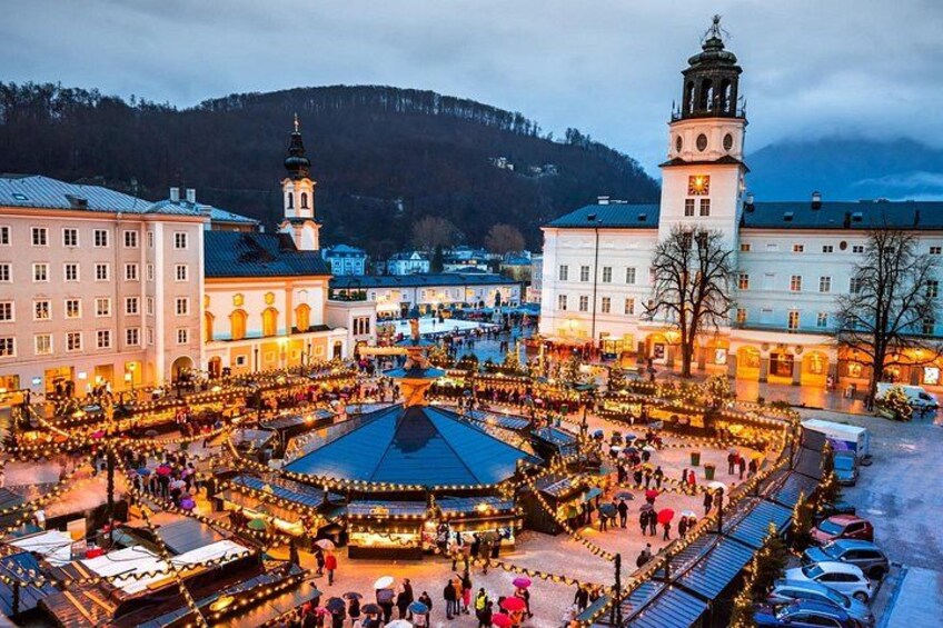 A festive square with illuminated stalls, historic buildings, and a clock tower. 3
