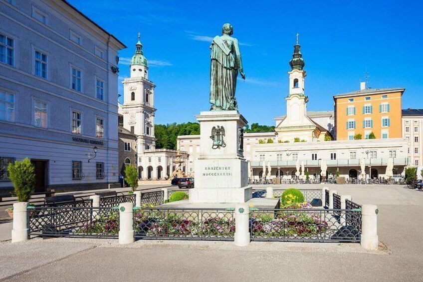 Una statua in una piazza, sullo sfondo edifici e una torre. 2