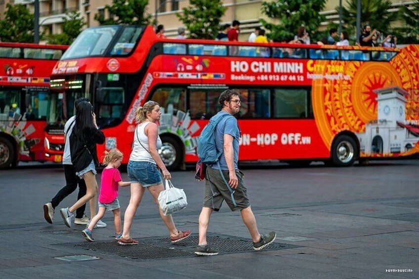 Une rue animée où circule un autobus à deux étages rouge, portant l’inscription « Visite de HÔ-CHI-MINH-VILLE ». 4