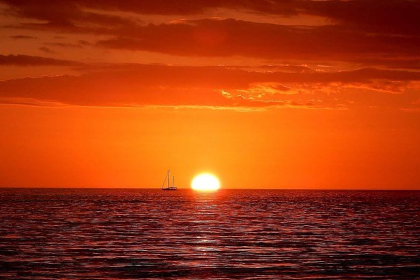 Tramonto sull'oceano con una barca a vela all'orizzonte. 5