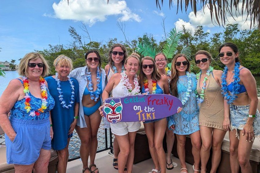 Eine Gruppe von Menschen auf einem Boot mit einem Schild, auf dem 'Gala Freaky on the Tiki' steht. 4