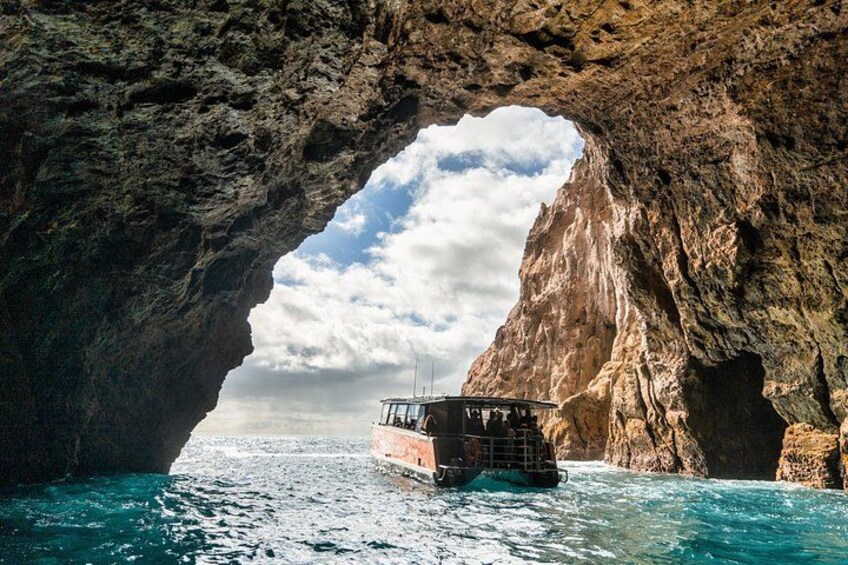 A boat navigating through a natural rock arch formation. 1