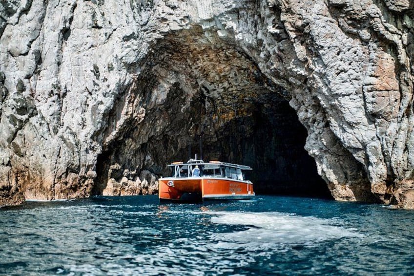 A boat navigating through a rocky cave entrance. 4