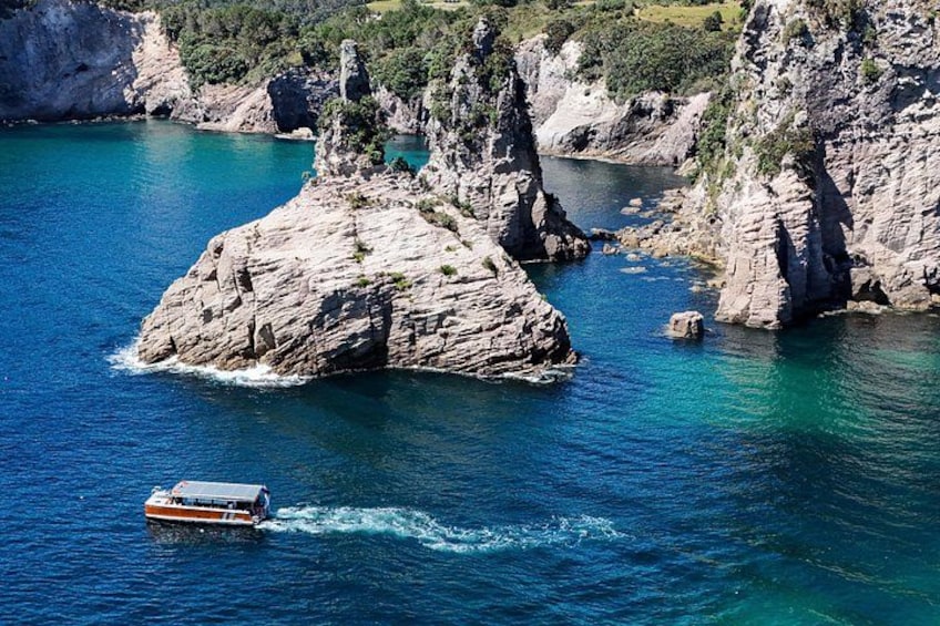 A boat on a turquoise sea with rocky cliffs in the background. 2