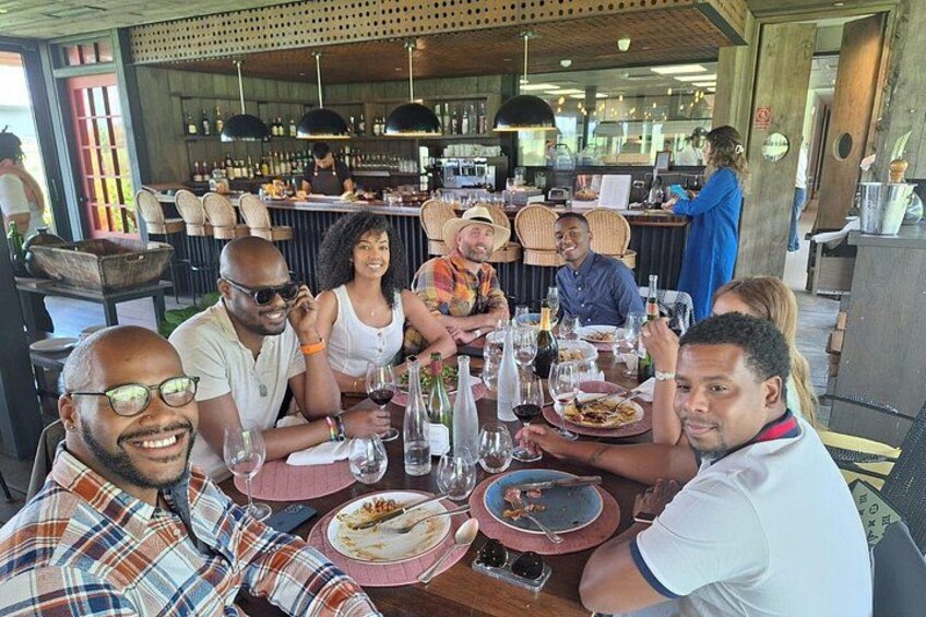 Een groep mensen dineert in een restaurant, met een bar op de achtergrond. 3
