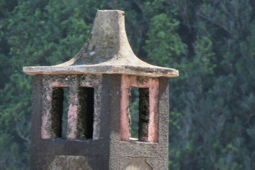 A weathered stone structure with a pointed roof and two vertical openings. 3
