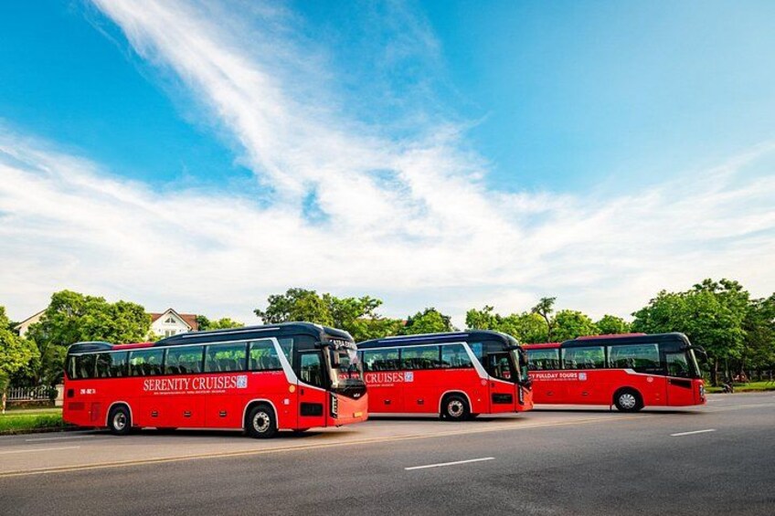 Three red buses parked on a road with trees and houses in the background. 5