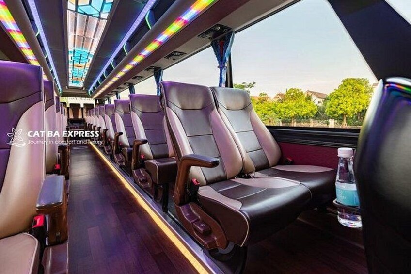 A train interior with leather seats, a wooden floor, and a window with a view of trees. 2