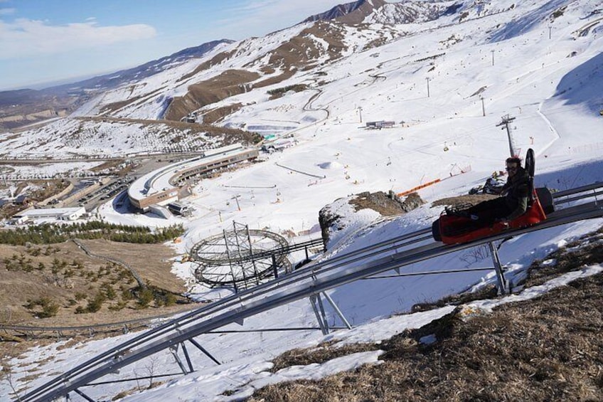 Eine verschneite Berglandschaft mit einer Seilbahn und einer Person in einem roten Sessellift. 3