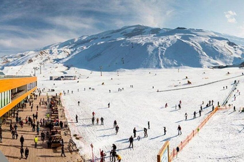 A snowy ski slope with skiers and a ski lift in the background. 4