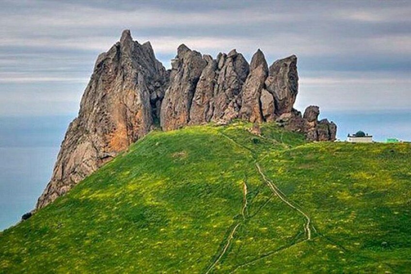 A grassy hill with a rocky outcrop. 5