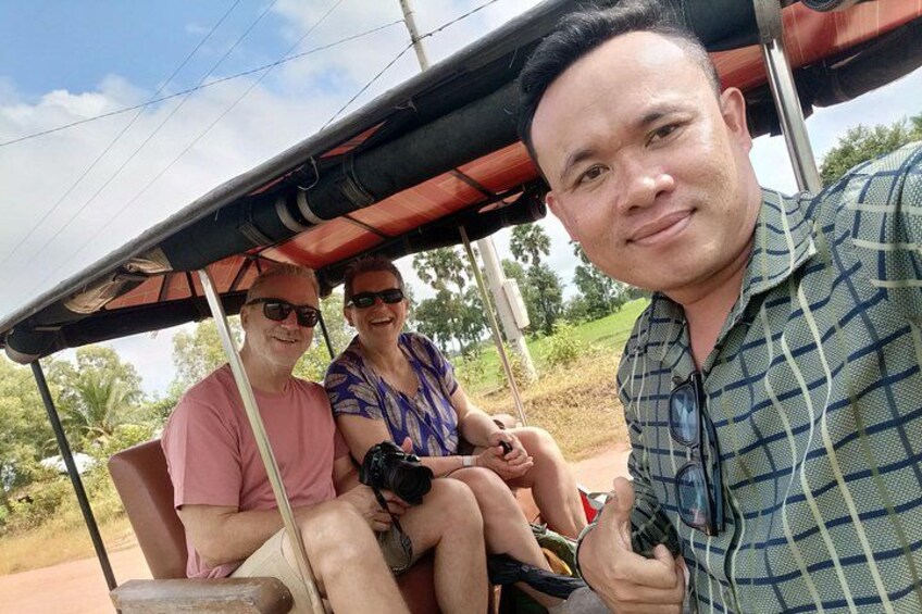 Three people in a covered vehicle, a rural landscape with trees and a clear sky. 2