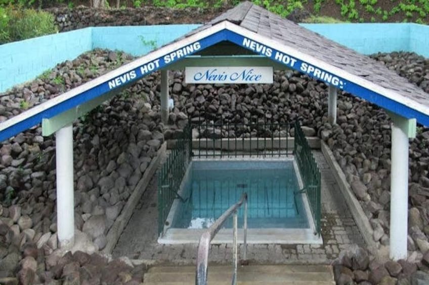 A hot spring with a blue roof and a sign that reads 'Nevis Hot Spring.' 5