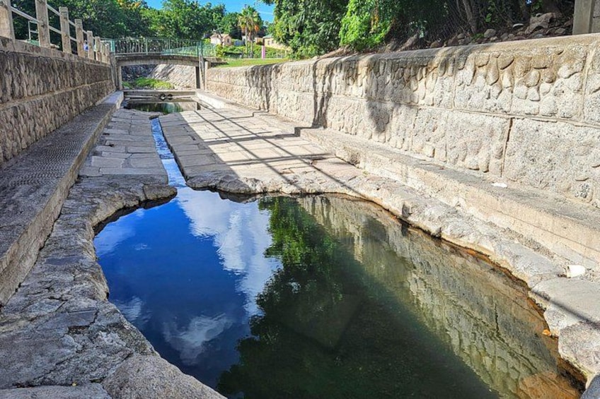 A stone-lined canal with a bridge in the background. 3