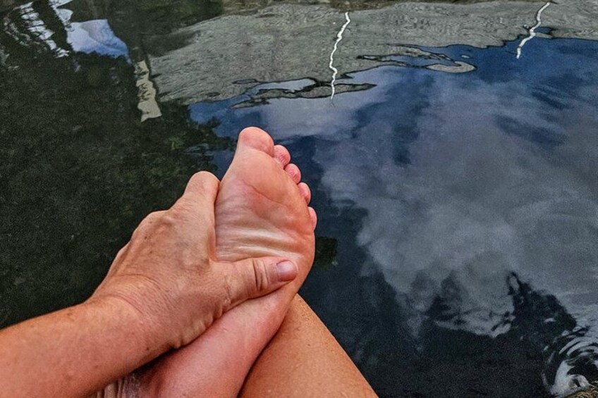 A pair of feet resting on a wet surface with cracks in the ground. 2