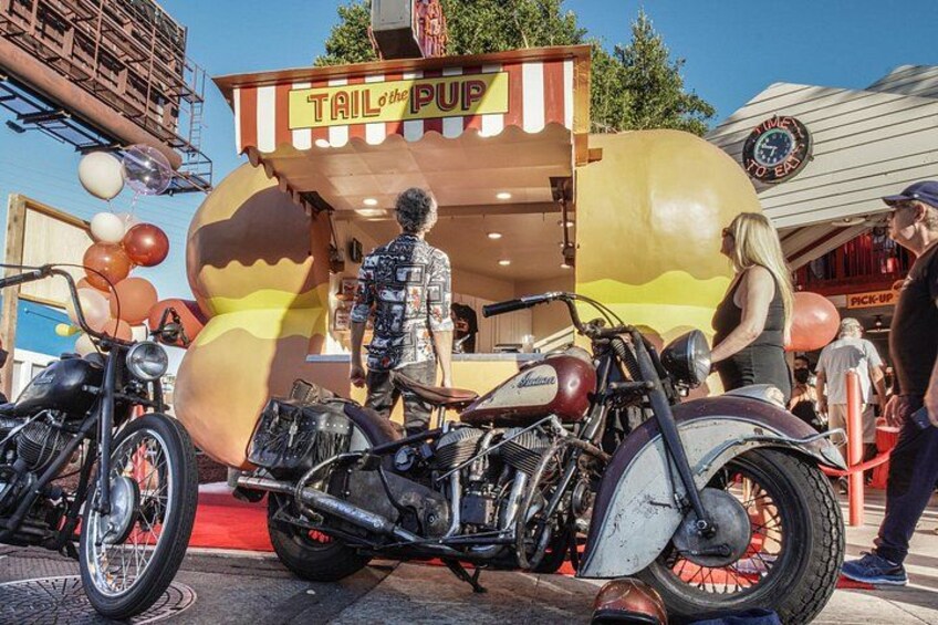 Una motocicleta antigua, un camión de comida y una persona de pie cerca del camión. 1