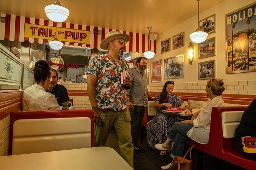 Ein Diner-Interieur mit roten Sitzbänken, einem 'TAILPUP'-Schild und Vintage-Dekoration. 3