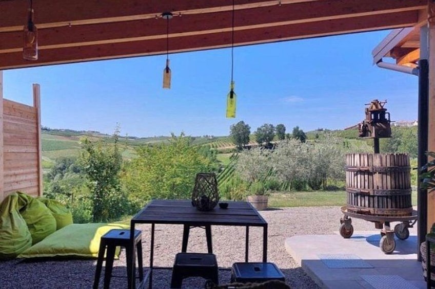 An outdoor patio with a table and chairs, a green bean bag, a wooden barrel, and a hanging light fixture. 1