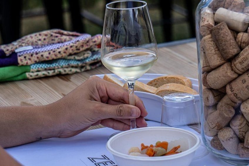 A hand holding a wine glass, a bowl of food, and a container of wine corks. 5