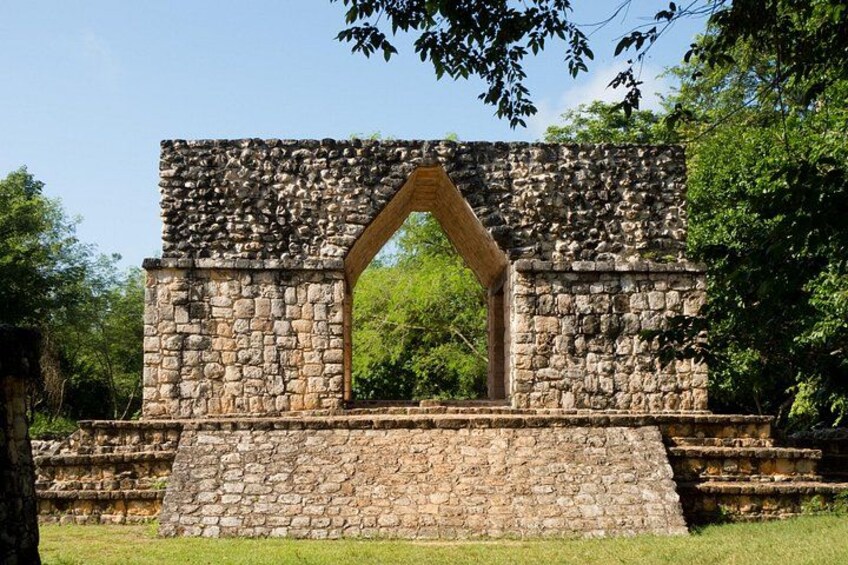 A stone structure with an archway, surrounded by greenery. 2