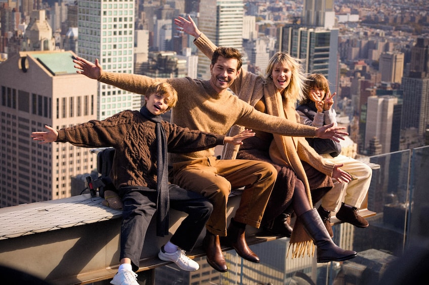 A group of people sitting on a ledge with a cityscape in the background. 2
