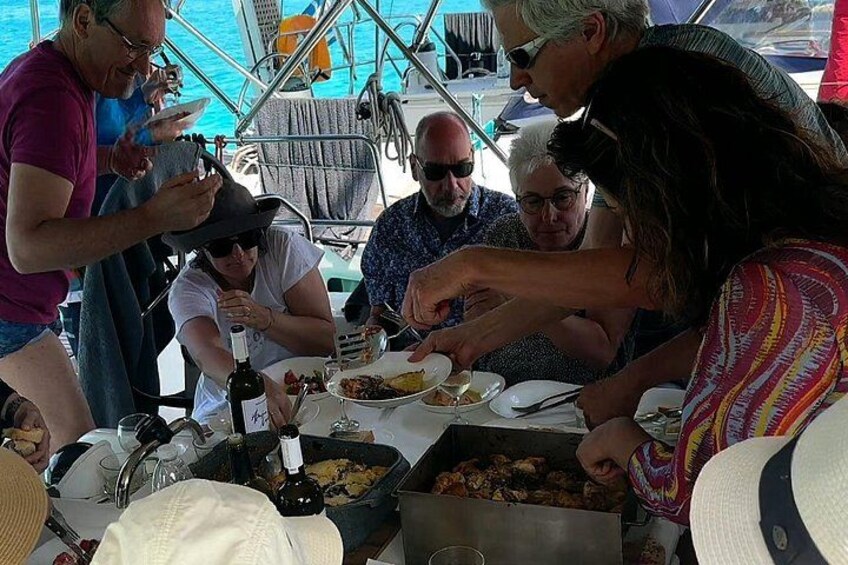 A group of people dining on a boat with a table set for a meal. 3