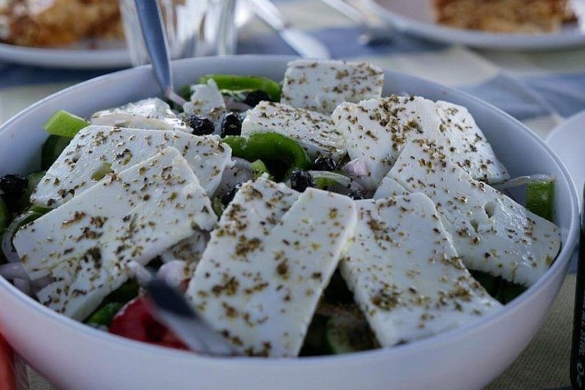 A bowl of salad with feta cheese, olives, and herbs. 2