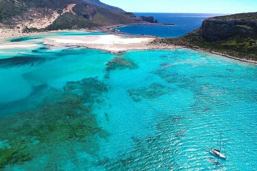 A coastal landscape with clear turquoise waters, a sandy beach, and a boat anchored near the shore. 1