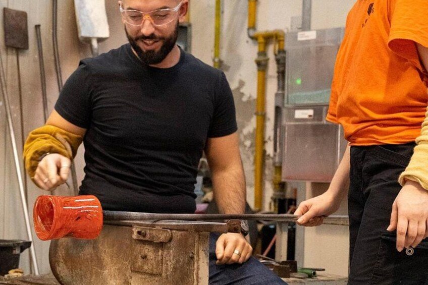 Une personne manipule un outil rouge sur un objet métallique dans un atelier. 2